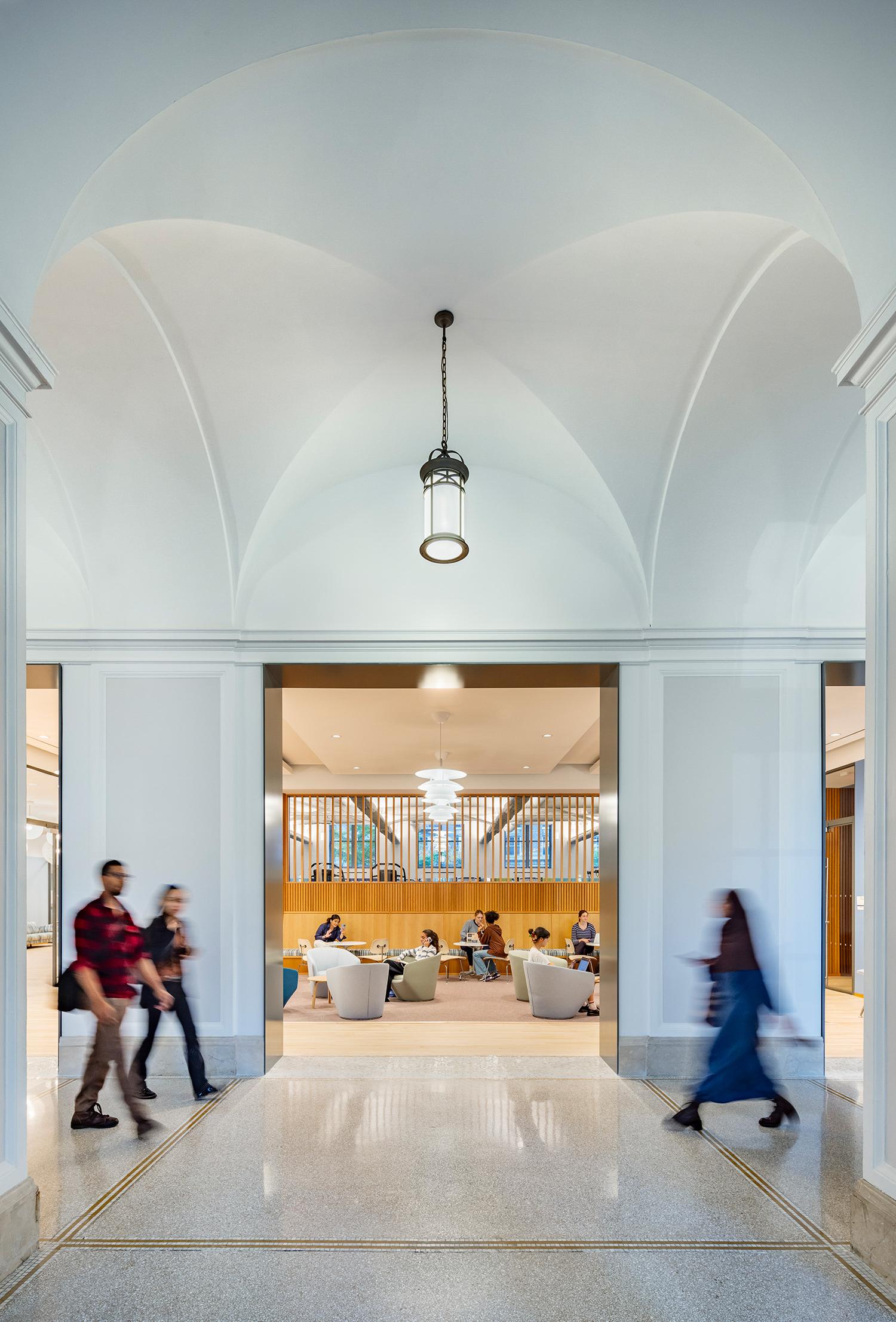 Students pass through the restored lobby. White walls and archways lead into the Lefrak center.