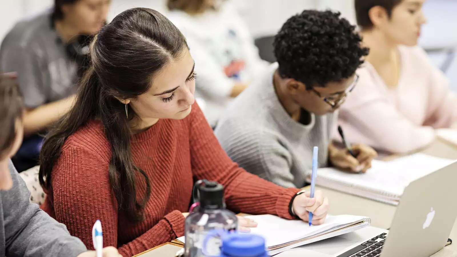 students in a classroom, writing in notebooks