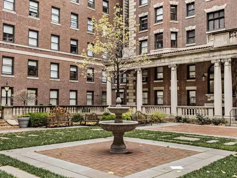 Shows Arthur ross courtyard fountain, pavers and grass in the middle of the quad of dorm buildings