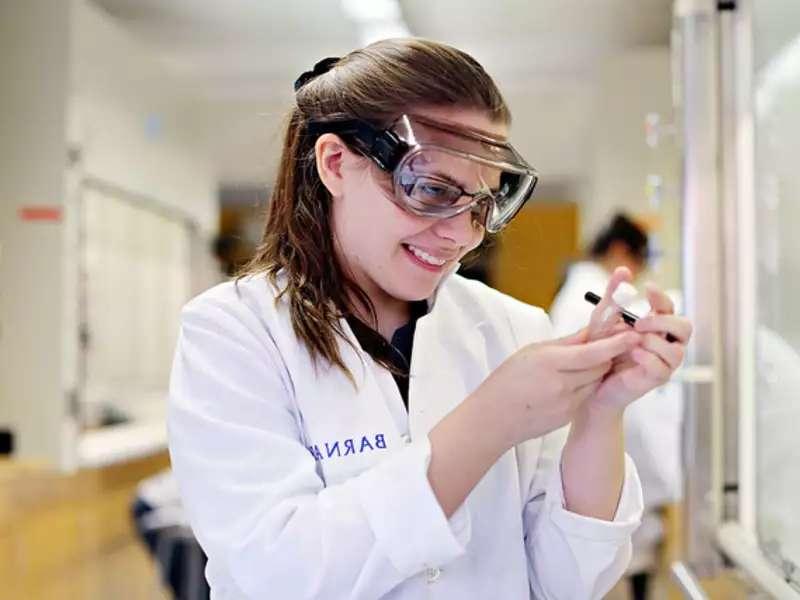 Student in a lab coat holding a test tube